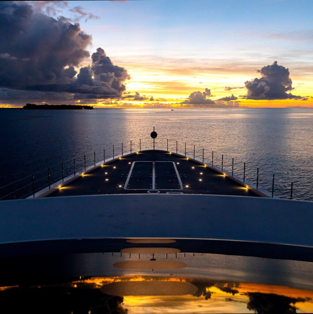 Yacht at sea with sunset and clouds.